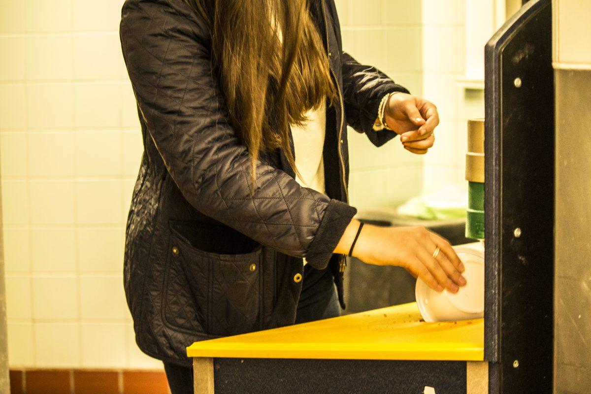 A student composts unused food in a Wellesley College dining hall. Photo by Megan Stormberg '18, Photo Editor