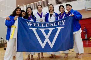 members of Karate Club hold up a Wellesley flag