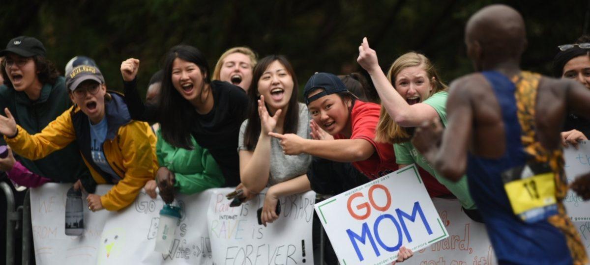 People with signs cheering on runners