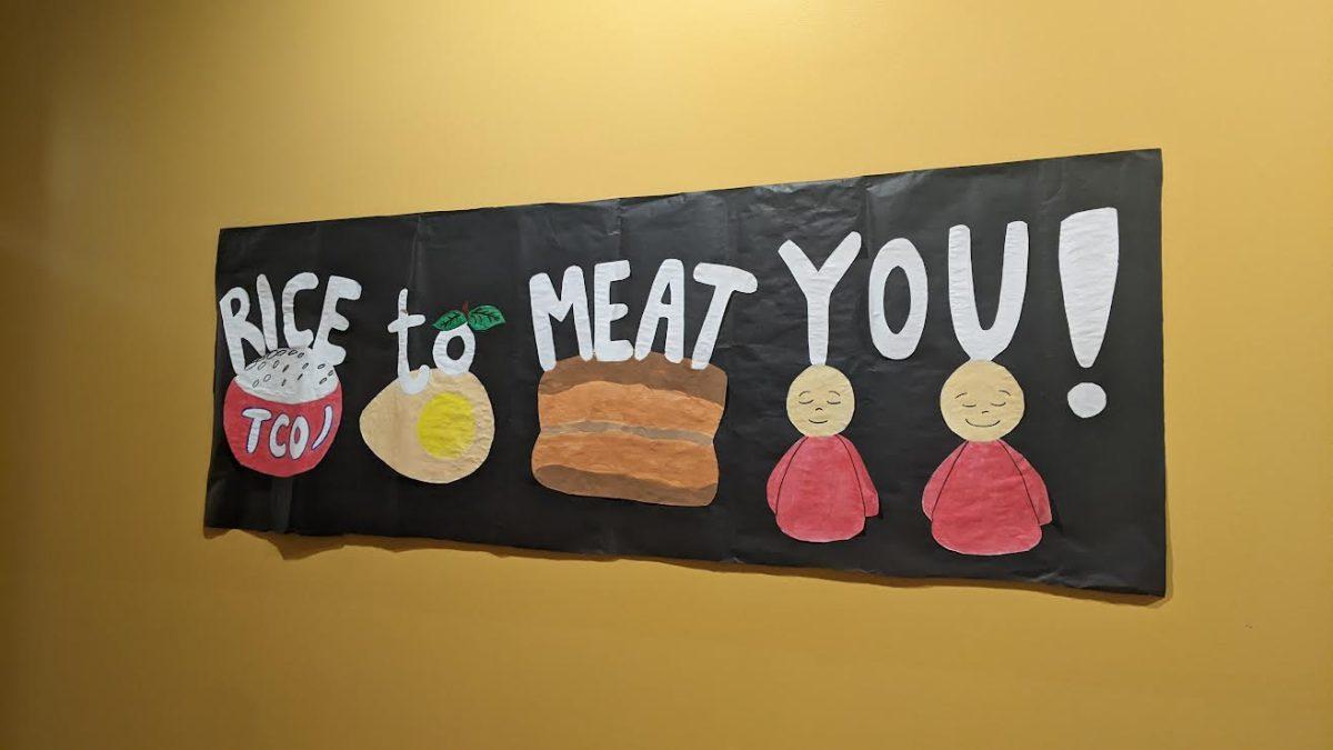 An image of a night market decoration. There are drawings of food, including a bowl of rice with "TCO" on the bowl and meat. White text reads "Nice to Meat You!"