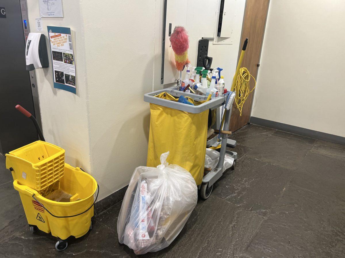 Trash bag, cleaning cart, and mop cart outside elevator in Bates Hall