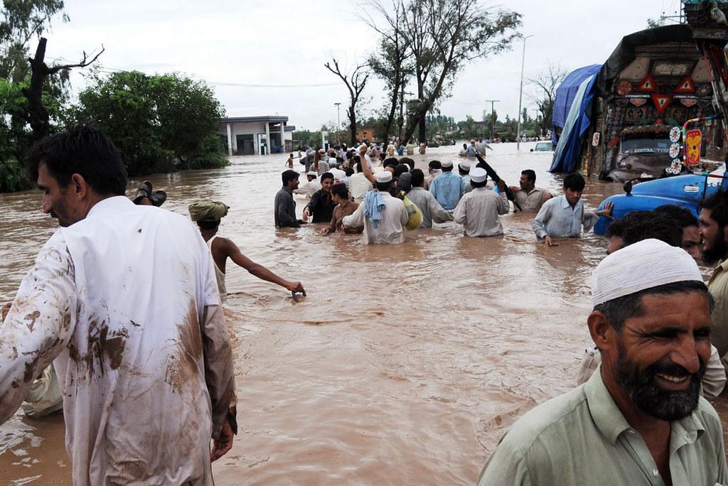 People wading through muddy floodwater in Pakistan