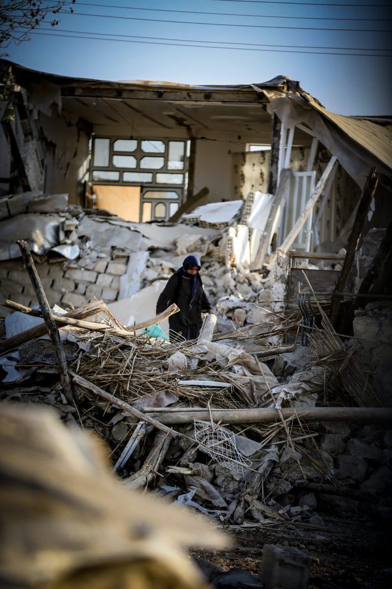 Woman walking through the rubble of a collapsed building