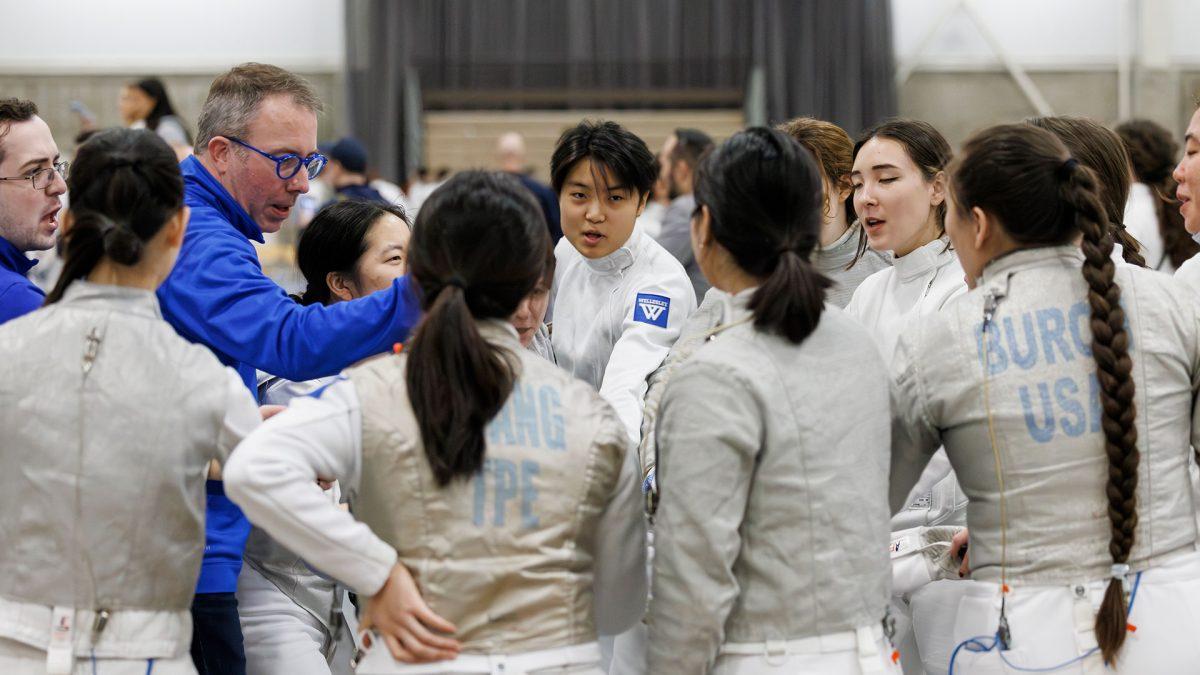 The Wellesley Fencing team gathers to cheer at a competition.