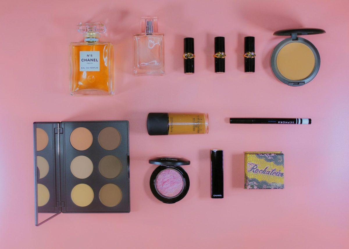 Photo of a variety of makeup products laid out neatly on a pink background